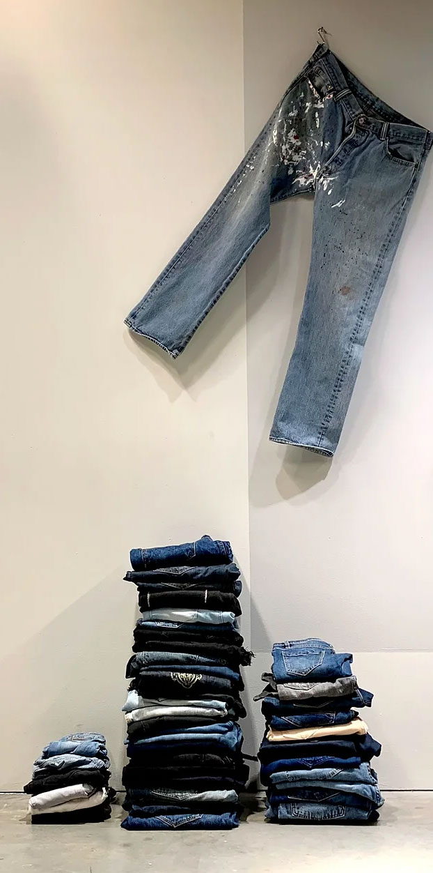A pair of jeans hanging over a stack of folded jeans.