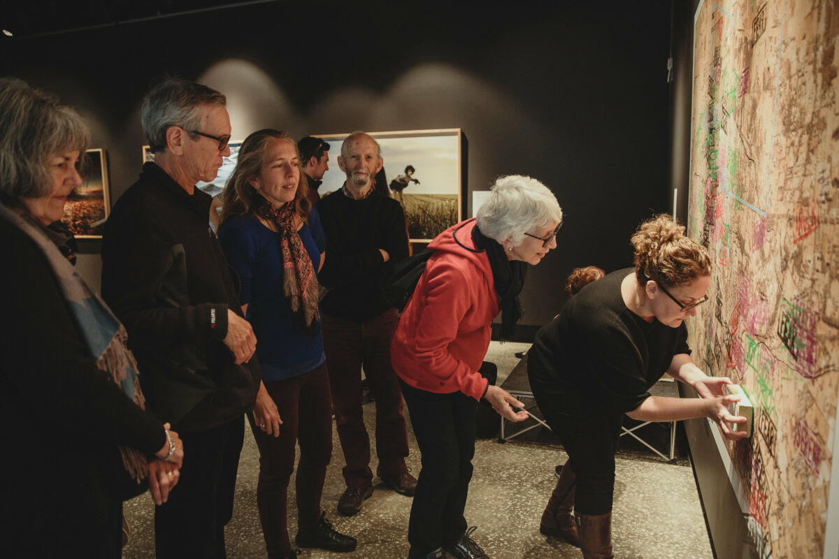 An artist and group of people are looking at a map.
