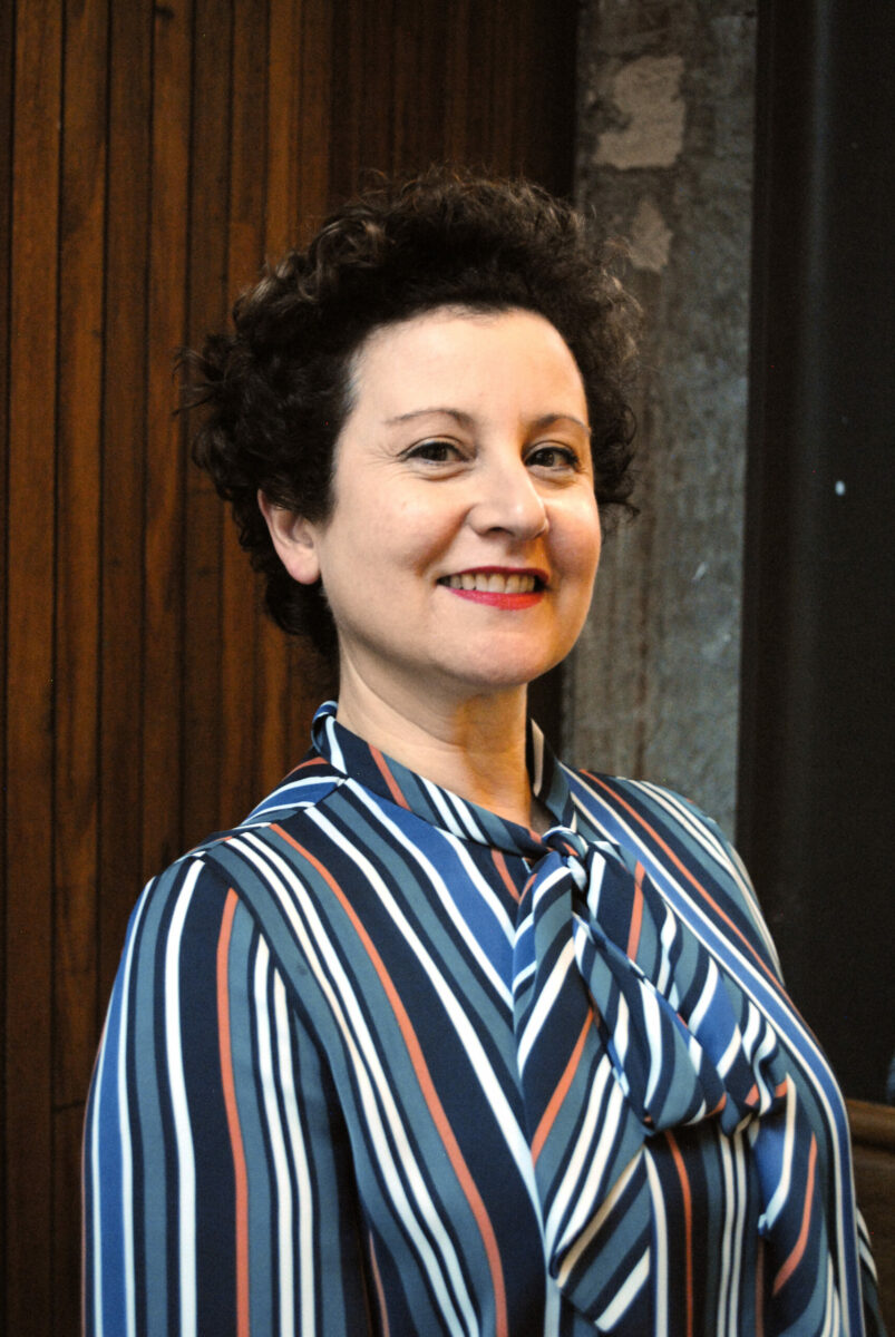 A woman smiling wearing a striped shirt.