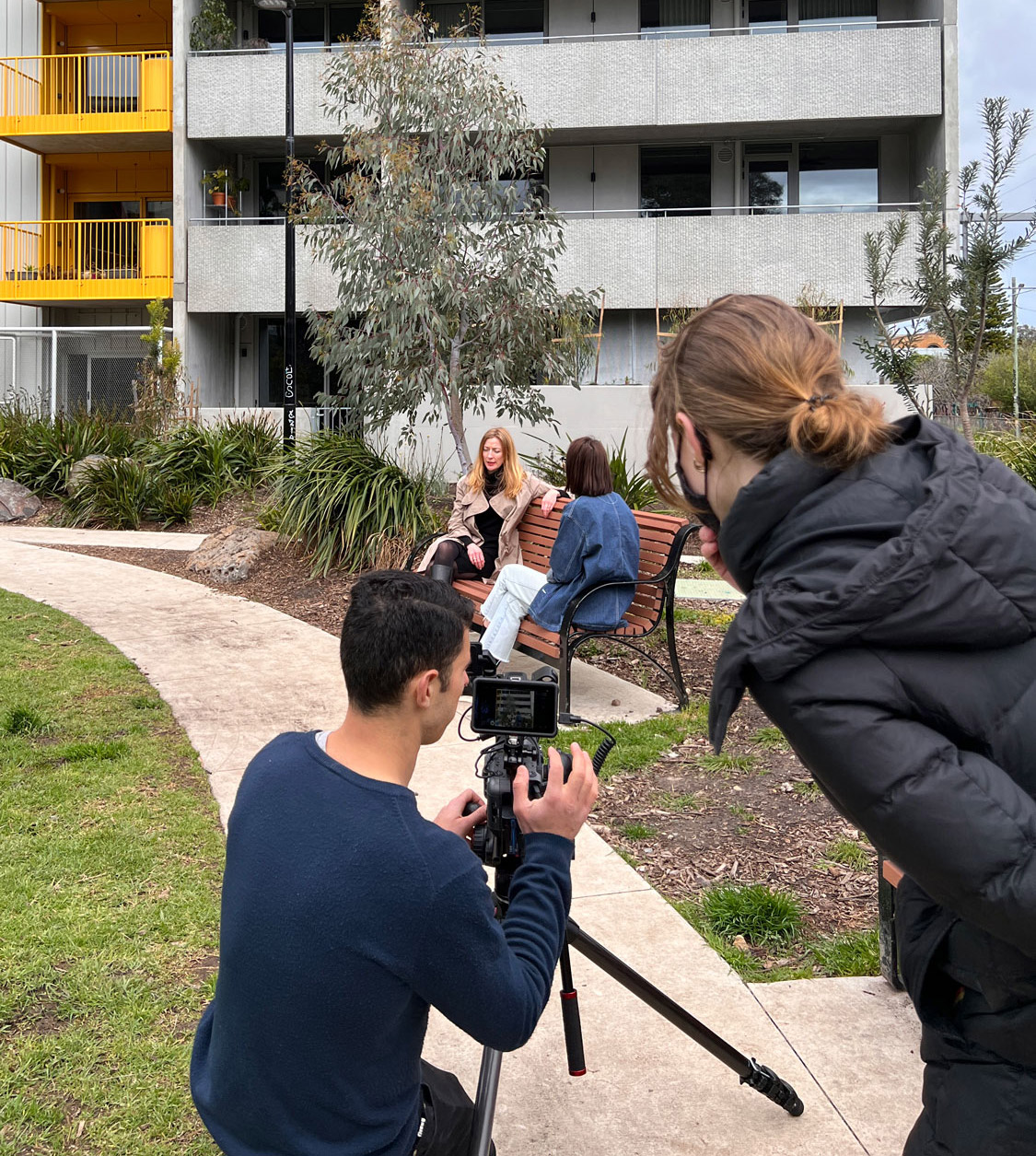 A photo shoot of two people doing an interview in a park.