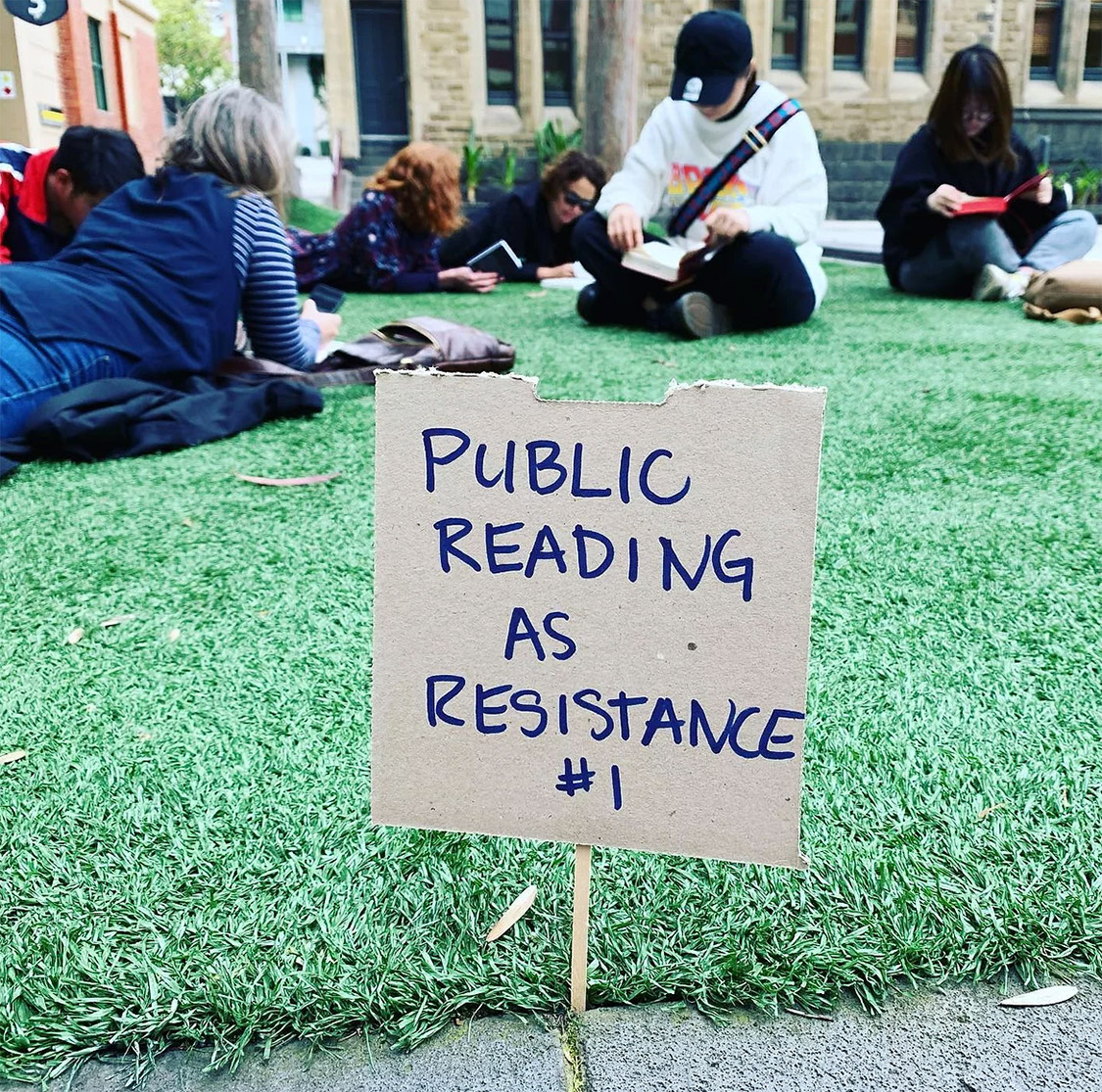 A sign on a grass lawn says public reading as resistance #1.