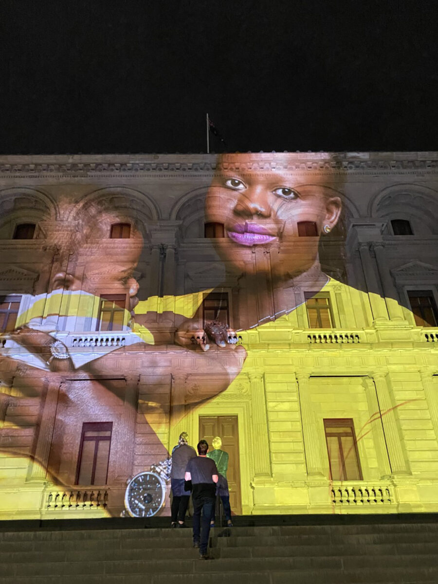 A portrait of a black woman and child projected onto the Treasury Building.