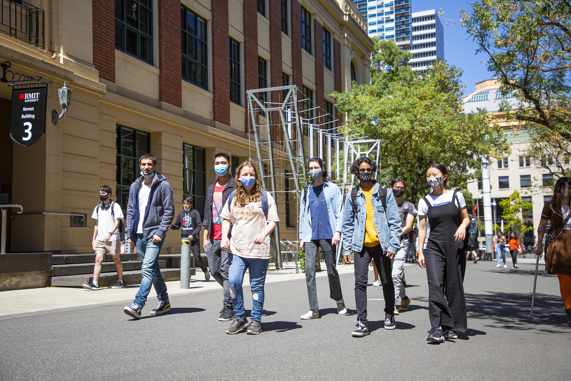 Students walking towards the camera, most wearing protective face masks.