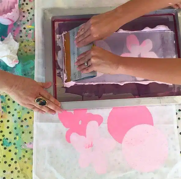 Hands screen printing on fabric.