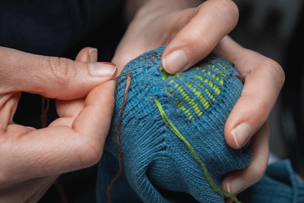 Hands mending a garment.